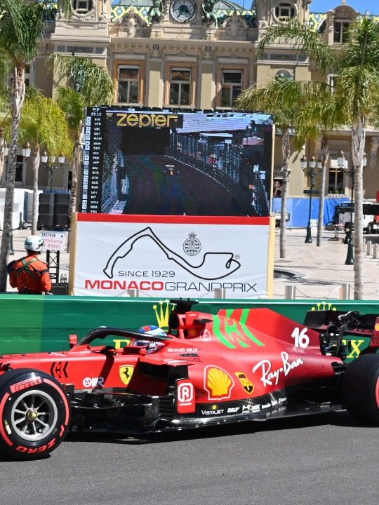 Ferrari F1 car on the Monaco circuit, with a rain screen in the background.