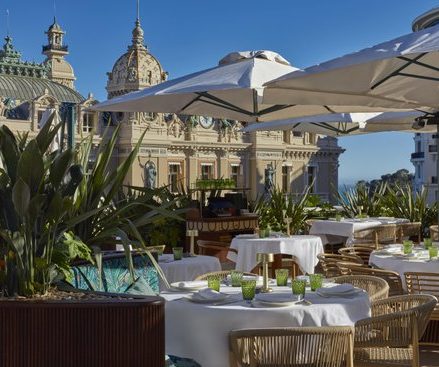 Elegant restaurant terrace with white tables and wicker chairs.