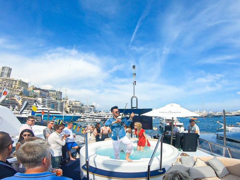 Party on a boat with people, a man entertaining on deck and a view of the sea.