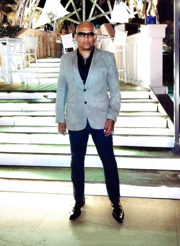 Man in gray suit, standing on luminous floor, with merry-go-round background.