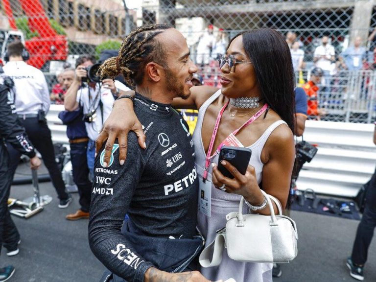 F1 driver with a person, happy embrace after a race. Festive atmosphere.