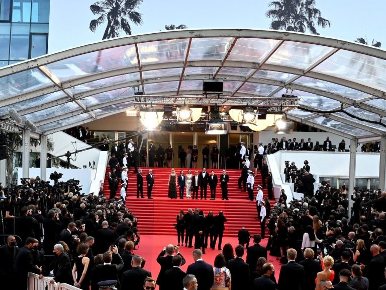 Red carpet and celebrities at a glamorous outdoor event.