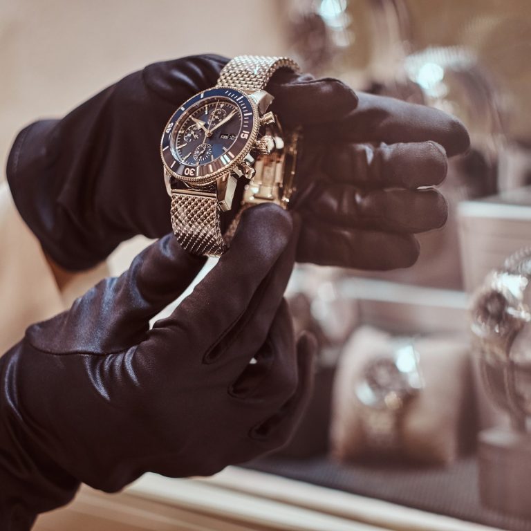 Elegant watch in gold, worn by gloved hands, displayed in a case.