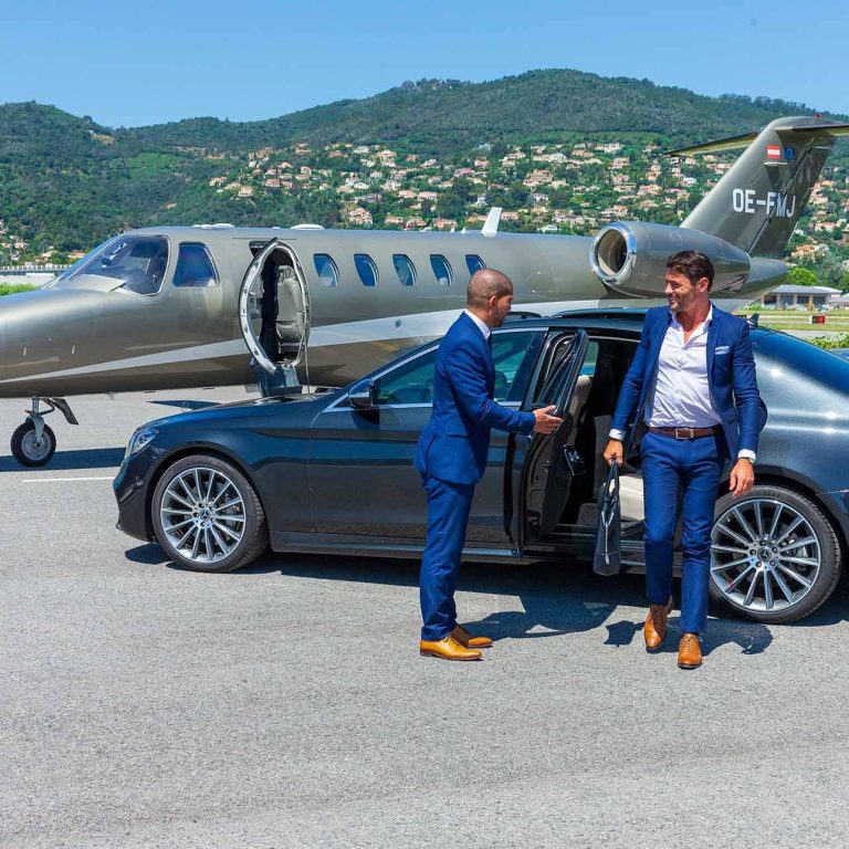 Man in suit getting out of a car, near a private jet on a runway.