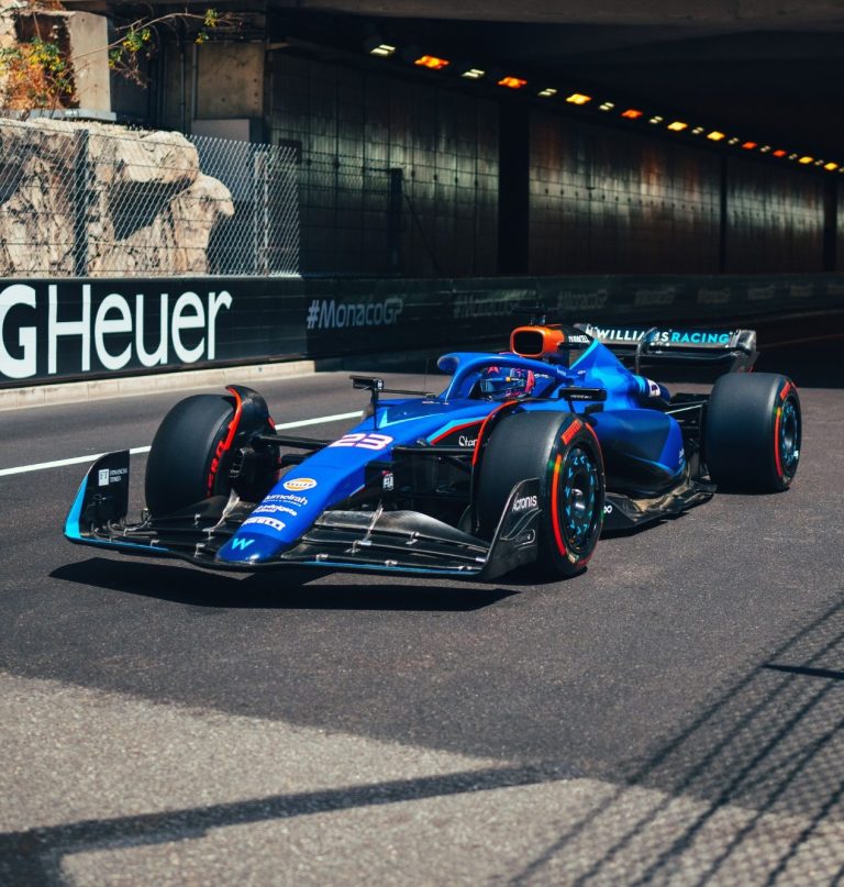 Blue and orange racing car entering a tunnel with concrete walls.