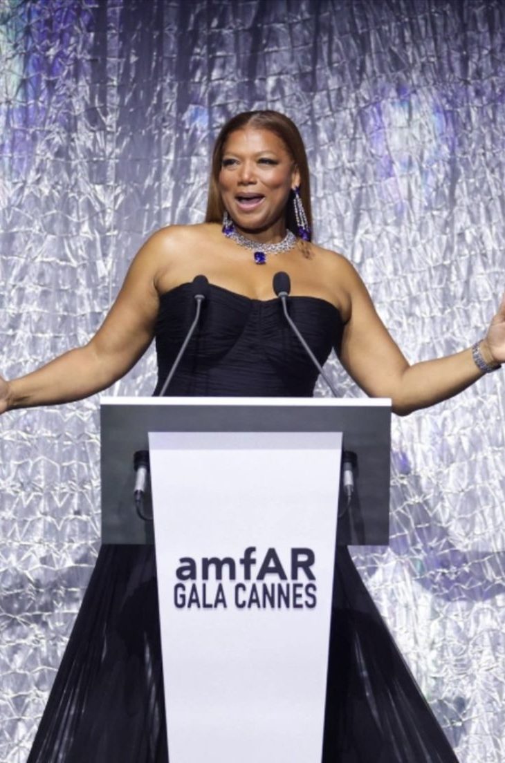 Woman in black dress speaking at the amfAR gala in Cannes.